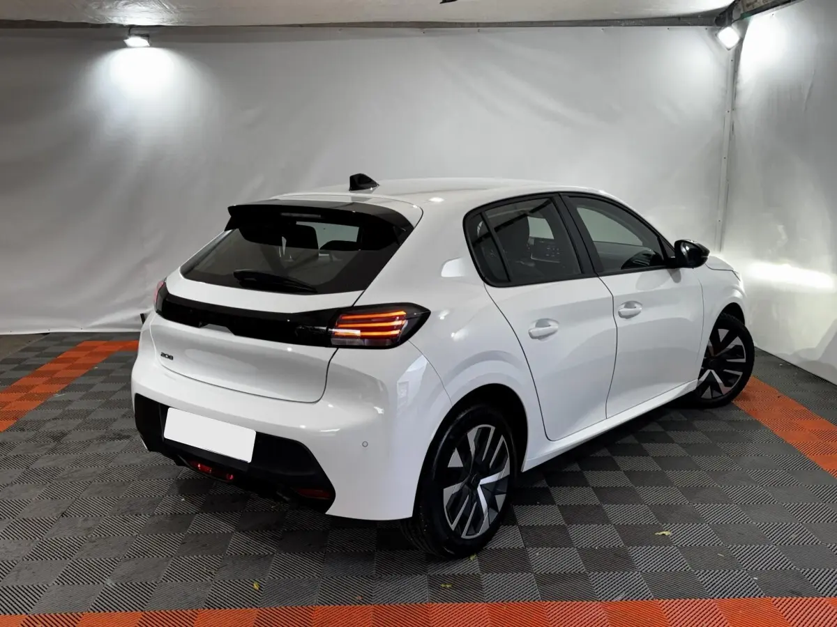 Peugeot 208 PureTech blanc vue 3/4 arrière droit dans un studio avec feux arrière LED allumés.