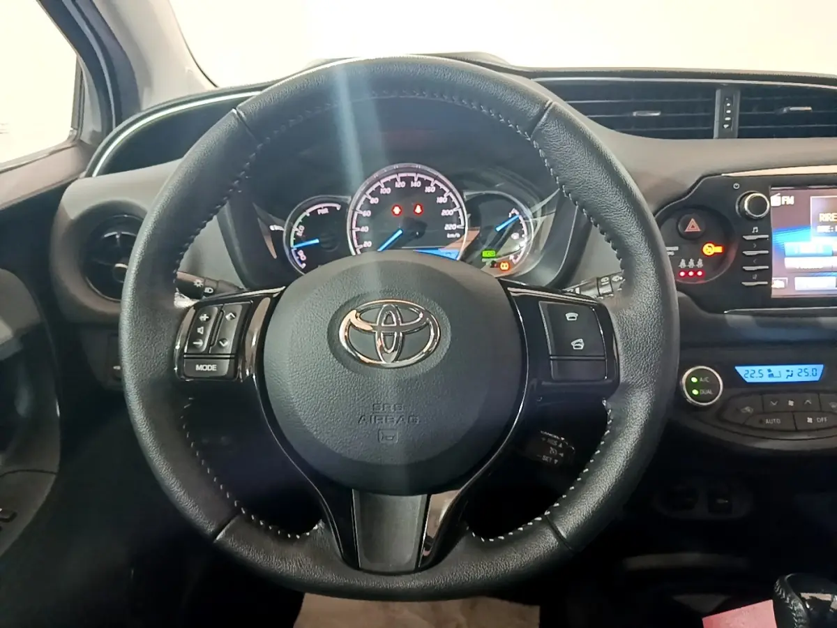 Volant cuir noir de Toyota Yaris 2019 vu de face, avec tableau de bord et écran tactile affichant la climatisation.