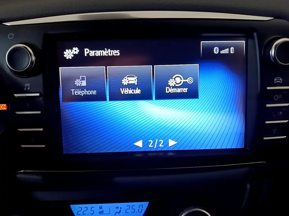 Écran tactile central affichant les paramètres du véhicule Toyota Yaris hybride blanc, vue intérieure frontale.