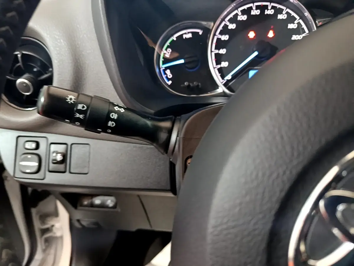 Vue rapprochée du tableau de bord et du volant cuir noir d'une Toyota Yaris blanche, affichage des compteurs lumineux.