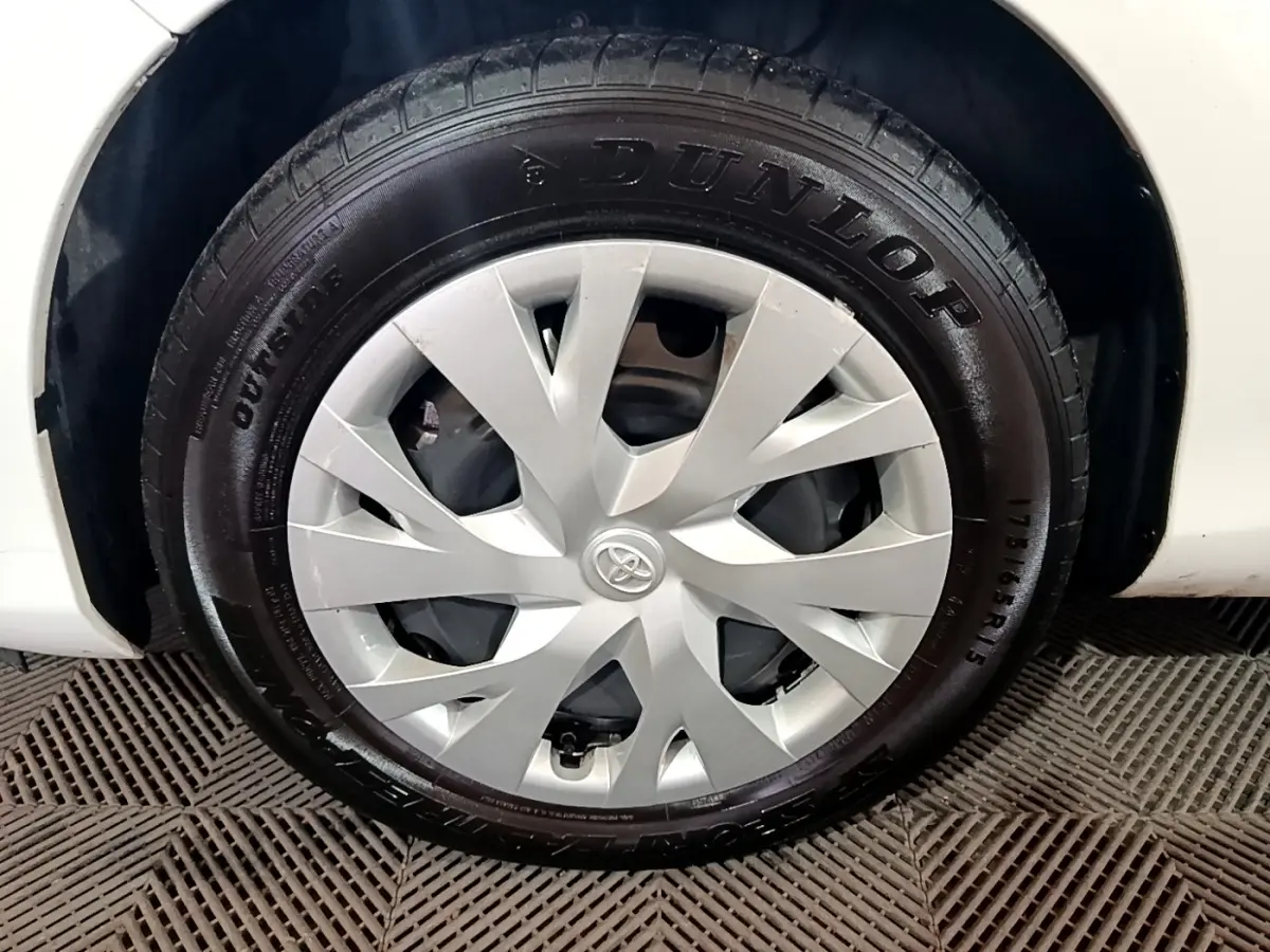 Gros plan sur la roue avant gauche blanche d'une Toyota Yaris 1.5 VVT-I Hybrid avec enjoliveur argenté et pneu Dunlop.