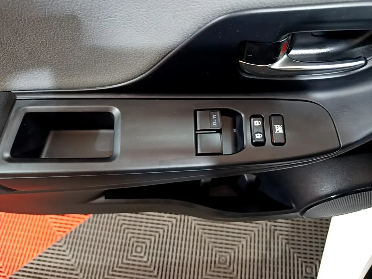 Gros plan sur la commande des vitres et verrouillage côté conducteur de la porte noire intérieure d'une Toyota Yaris blanche 2019.