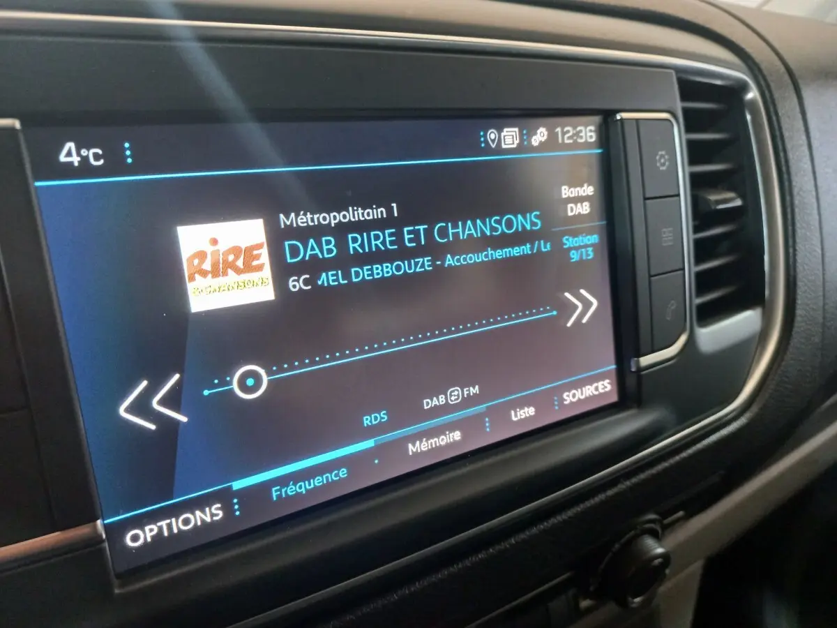 Écran tactile multimédia du tableau de bord du Peugeot Traveller gris clair, affichant une station radio DAB.