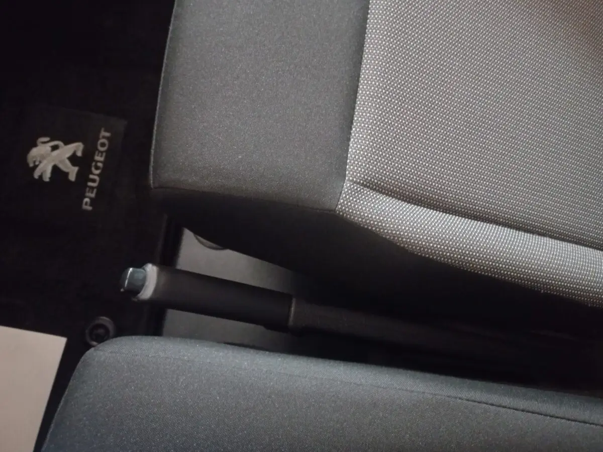 Gros plan intérieur sur le frein à main entre les sièges avant gris foncé du Peugeot Traveller 2021.