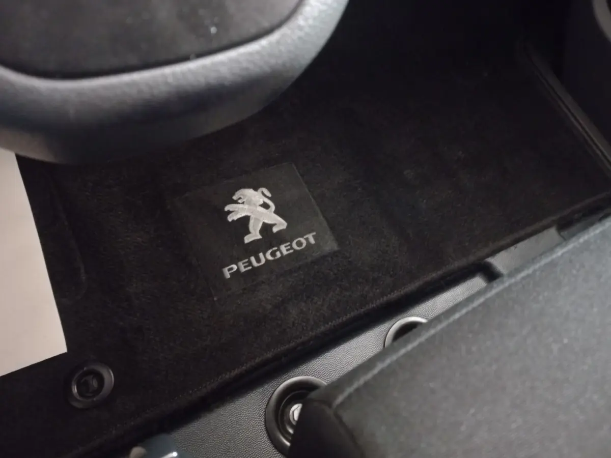Vue rapprochée du tapis de sol noir avec logo Peugeot à l'avant gauche du Peugeot Traveller gris clair 2021.