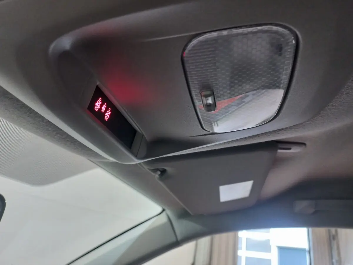 Vue intérieure du plafond avant du Peugeot Traveller gris clair 2021, montrant la console de plafonnier avec éclairage rouge et pare-soleil.