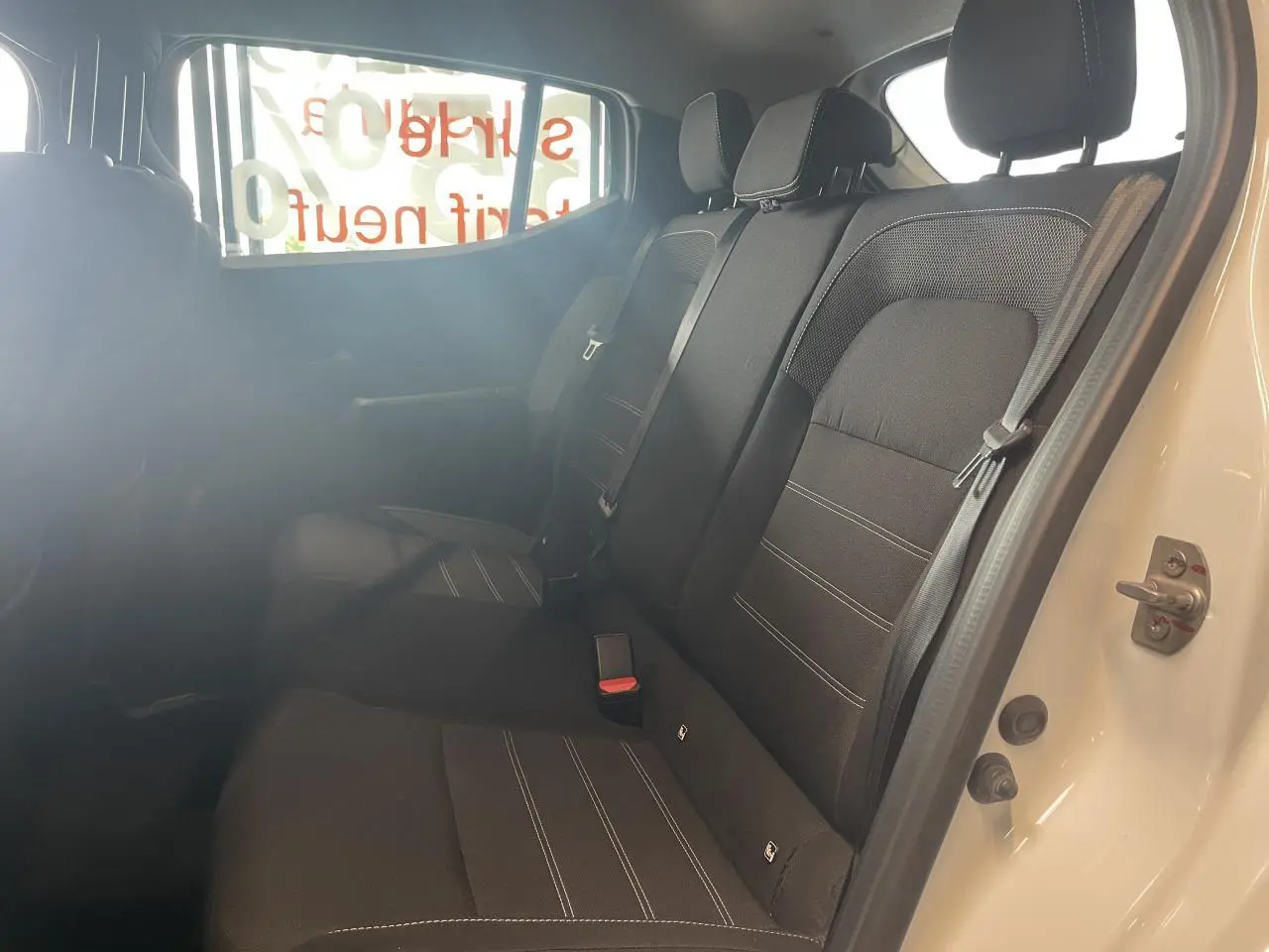 Vue intérieure côté droit de la banquette arrière noire avec ceintures de sécurité d'une Dacia Sandero blanche 2024.