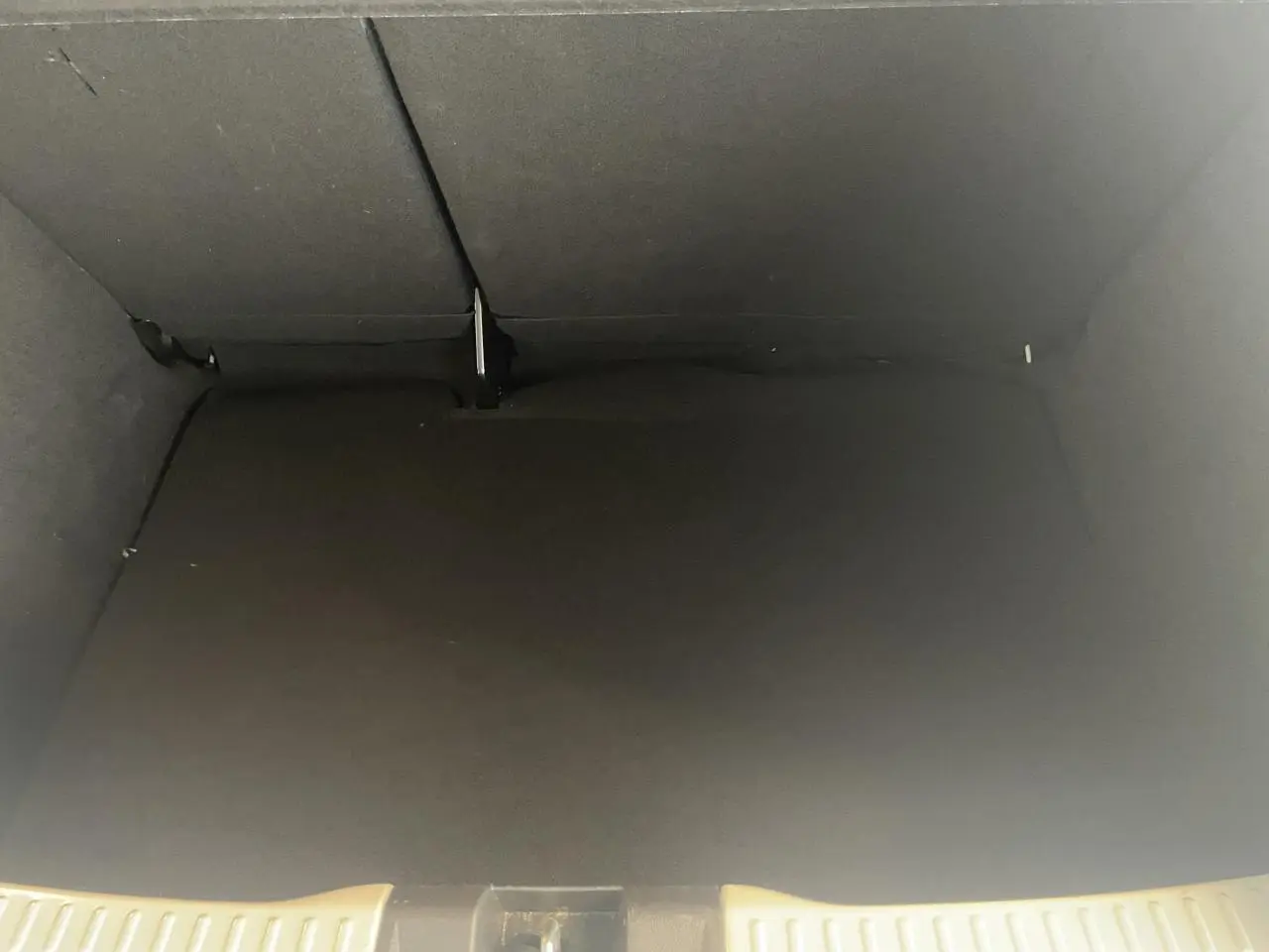Vue intérieure du coffre noir spacieux de la Dacia Sandero 2024, version Expression blanche, avec banquette arrière rabattue.