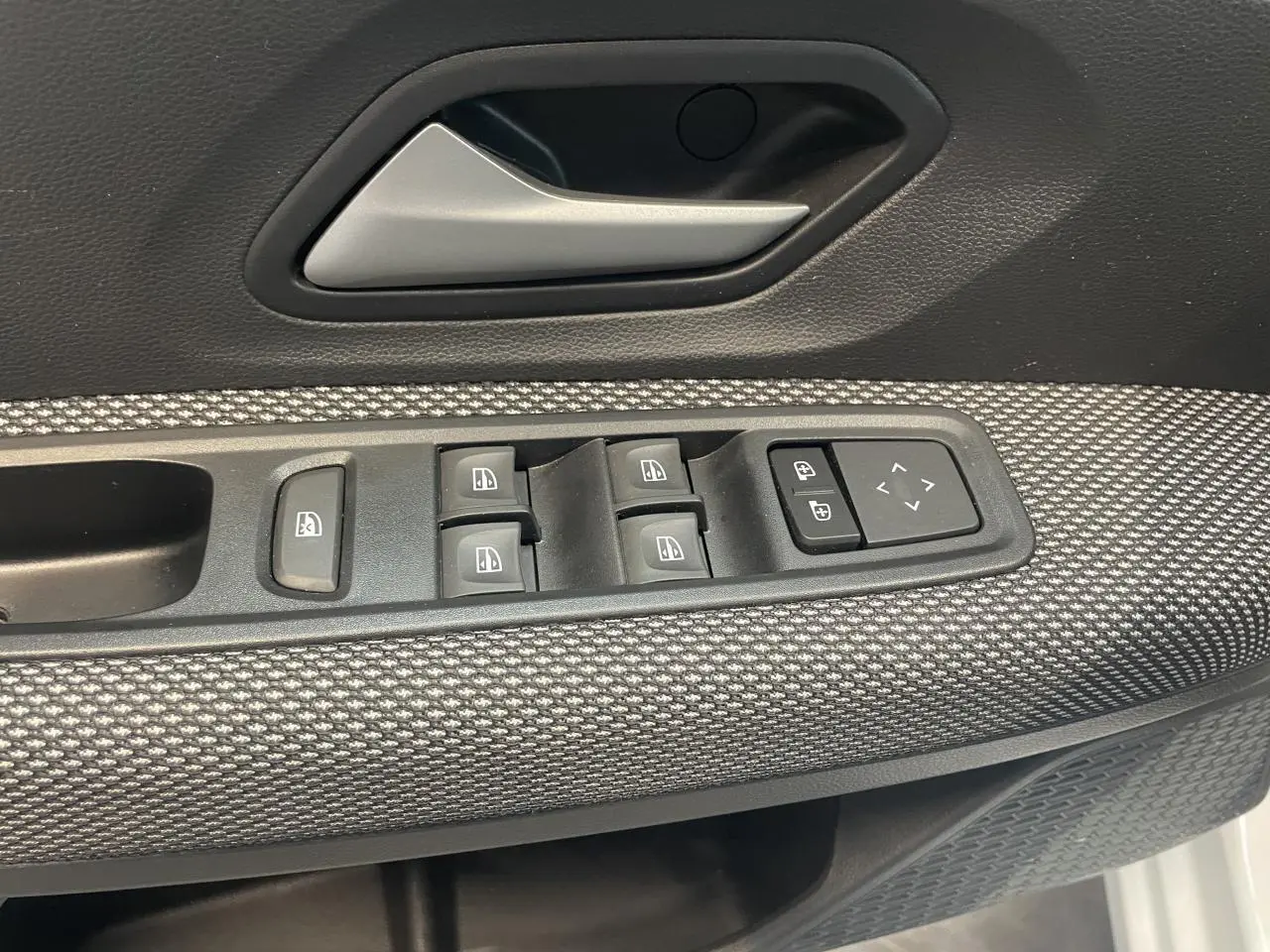 Détail de la porte avant gauche de la Dacia Sandero 2024, avec commandes de vitres et poignée argentée.
