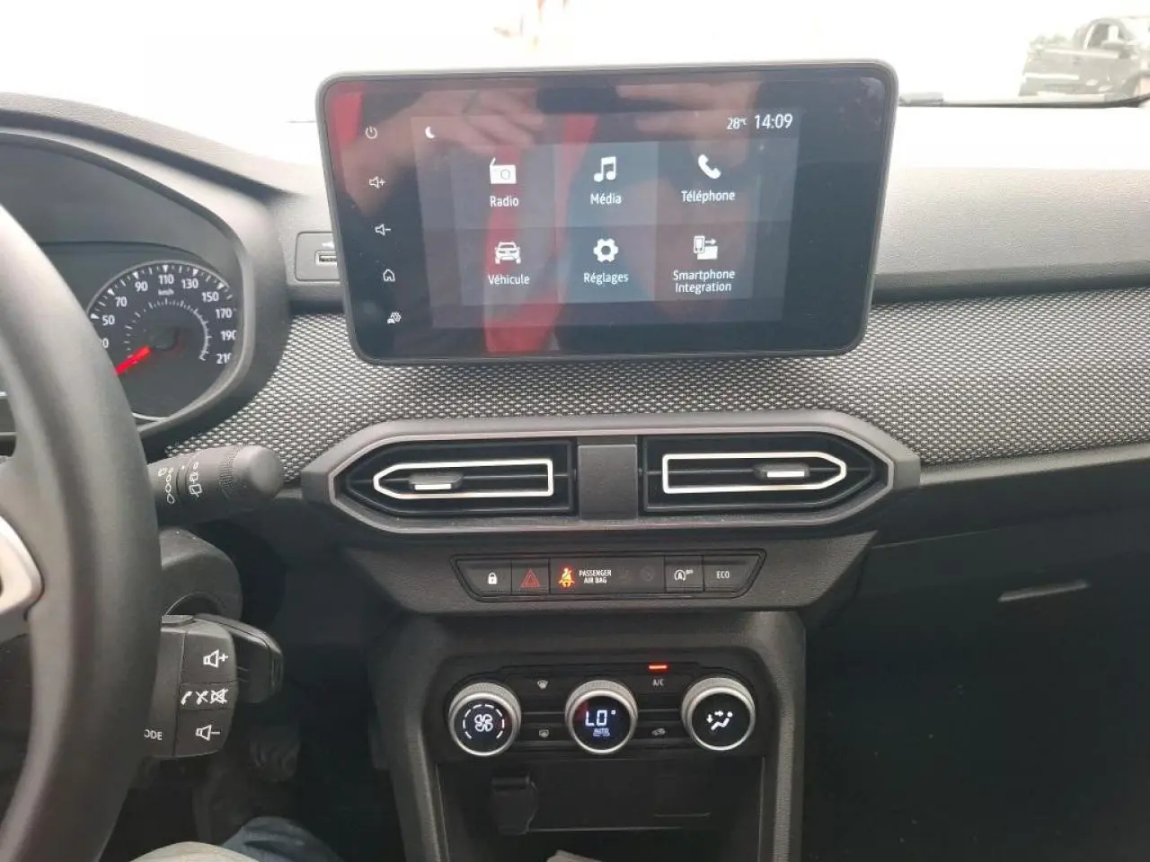 Vue intérieure du tableau de bord de la Dacia Sandero 2024 avec écran tactile et commandes de climatisation.
