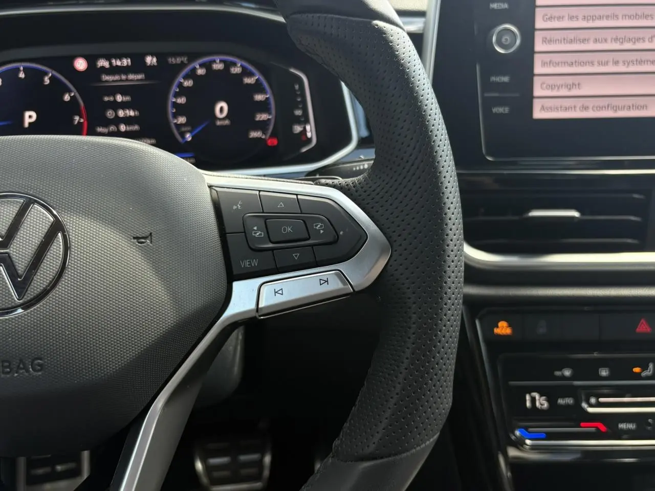 Gros plan sur le volant cuir perforé et le tableau de bord digital du Volkswagen T-Roc 2025 noir intense, version R-Line.