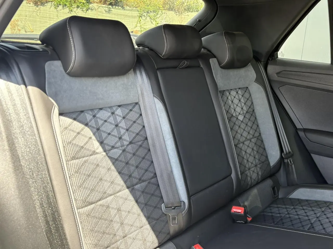 Vue intérieure arrière du Volkswagen T-Roc 2025 montrant les sièges cuir et alcantara gris et noirs avec surpiqûres contrastantes.