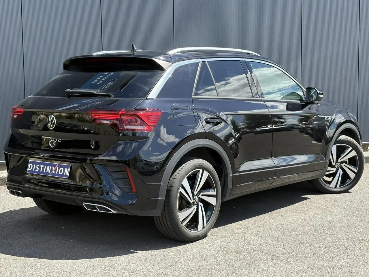 Vue 3/4 arrière droite d’un Volkswagen T-Roc noir intense avec jantes alliage 18 pouces et finitions R-Line visibles.