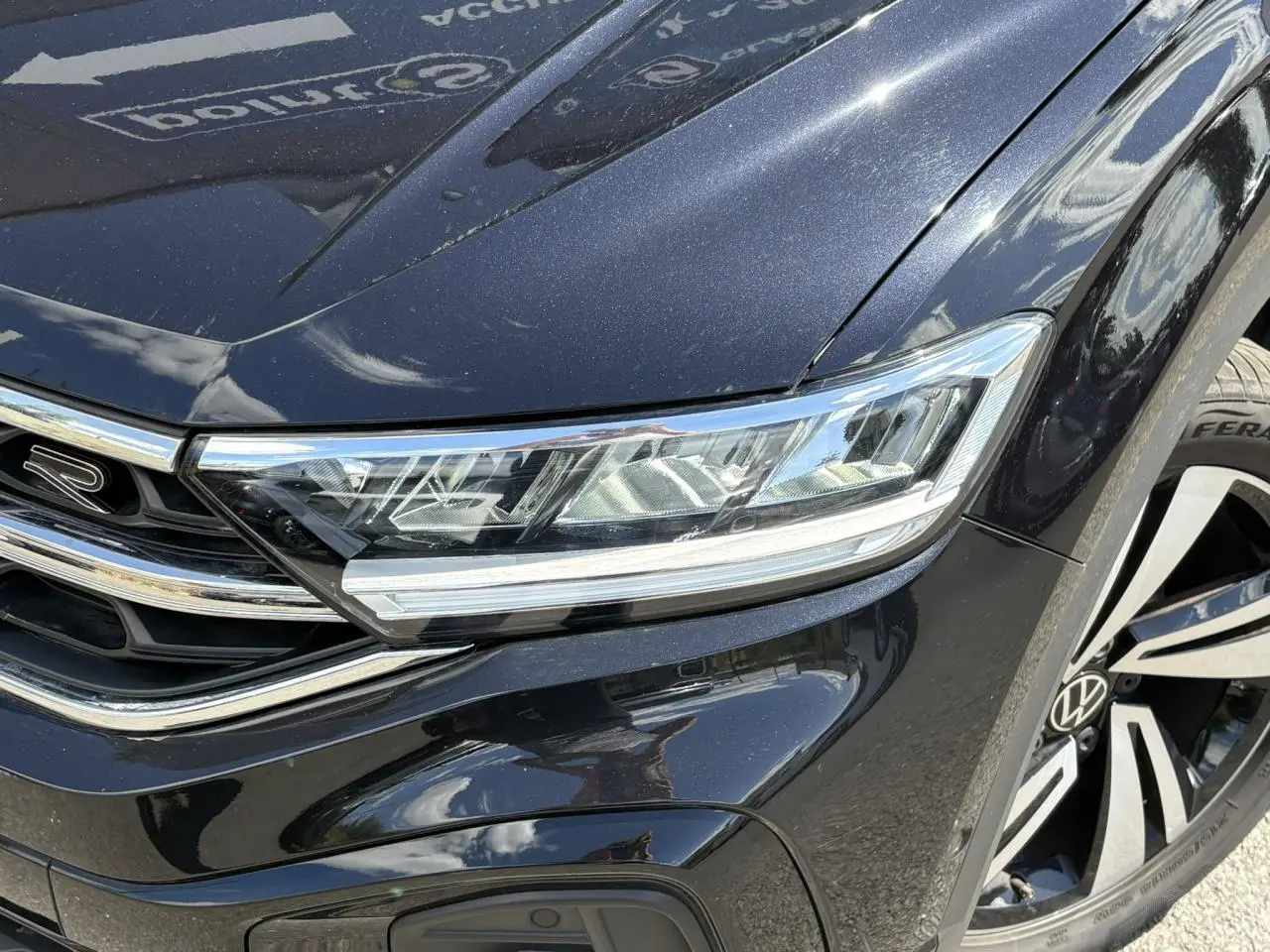 Gros plan sur l'avant droit noir intense du Volkswagen T-Roc 1.5 TSI R-Line avec phares LED et jante alliage Nevada.