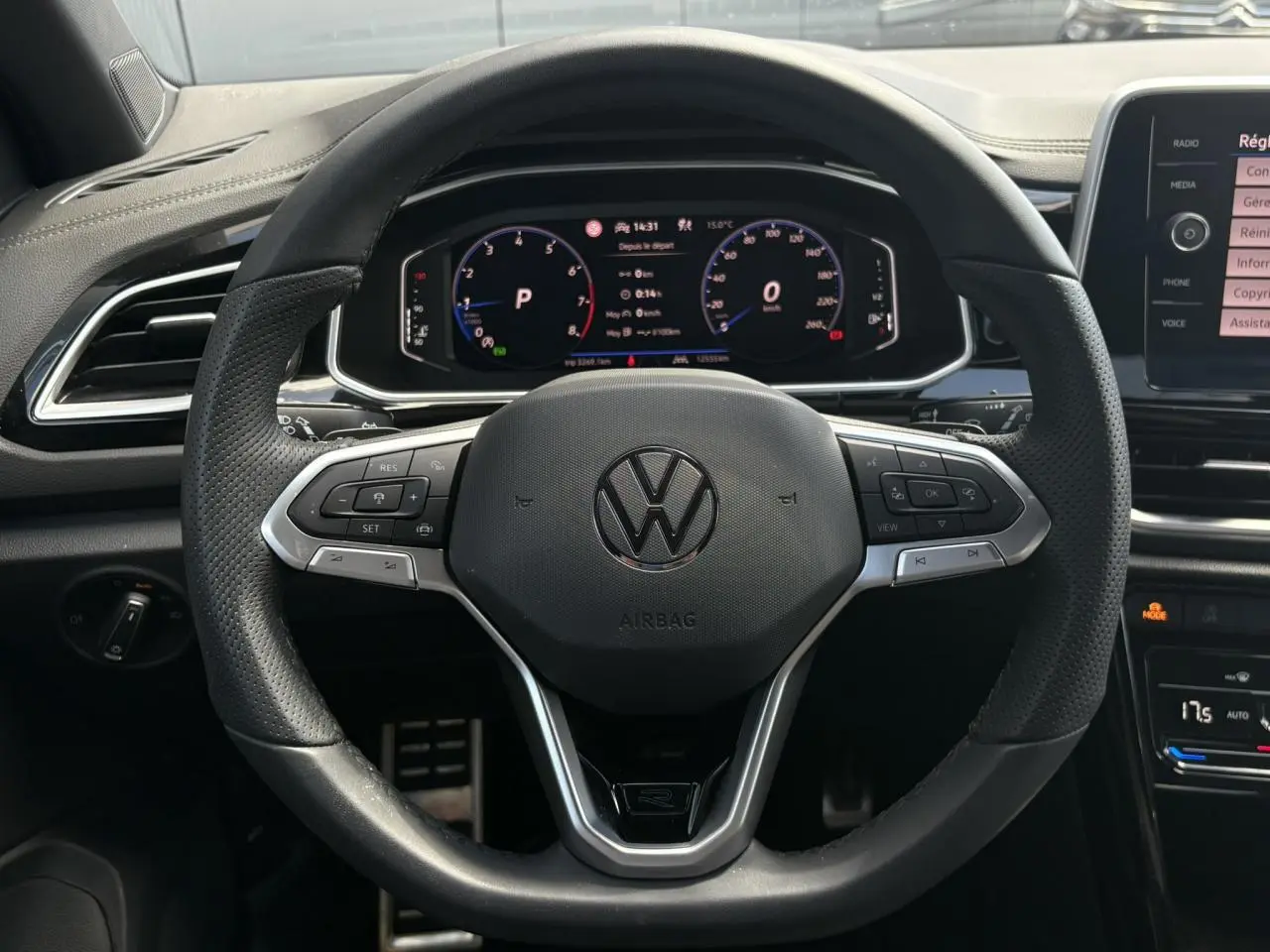 Vue frontale du volant cuir noir R-Line de Volkswagen T-Roc 2025 avec tableau de bord digital et commandes intégrées.