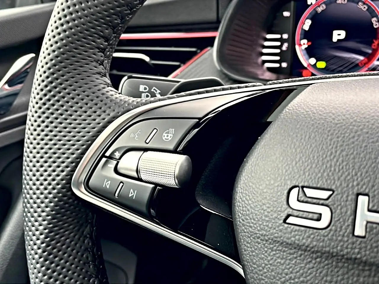 Gros plan sur la partie gauche du volant cuir perforé du Skoda Kamiq blanc nacré, avec commandes multifonctions et palettes.