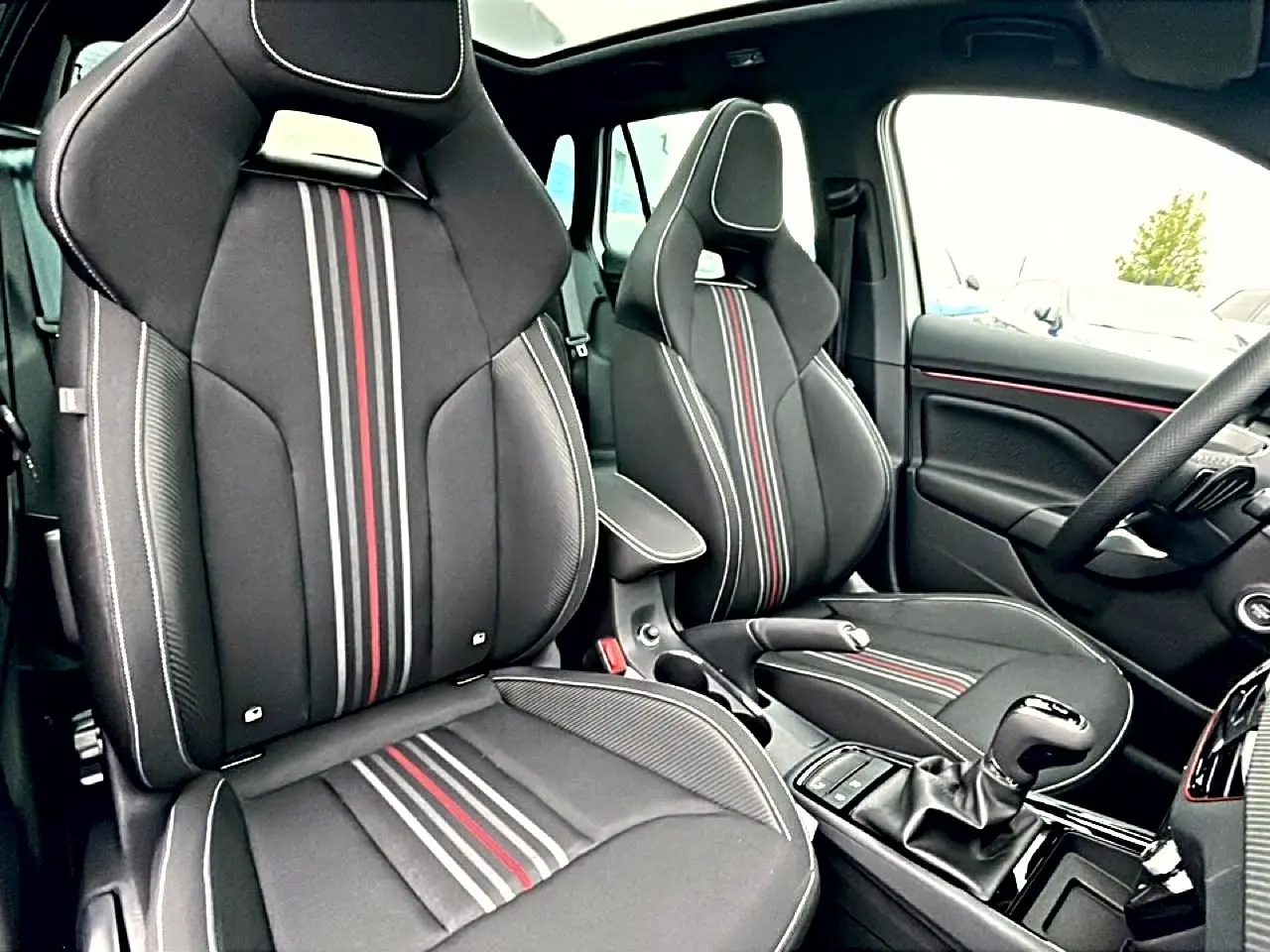 Intérieur SKODA KAMIQ Monte Carlo 2026, vue côté droit sur sièges sport noirs avec bandes rouges et grises.