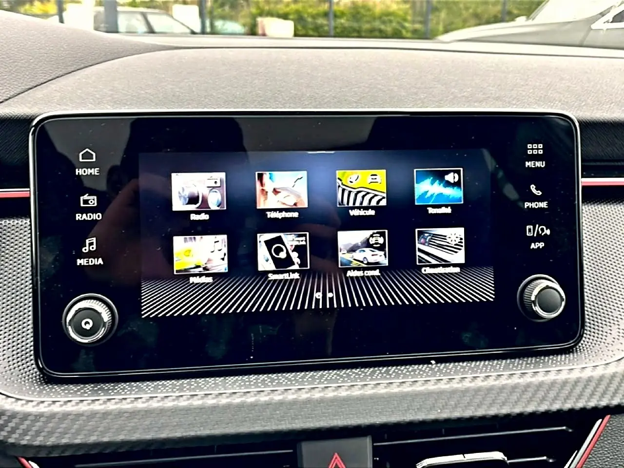 Écran tactile central du tableau de bord du Skoda Kamiq blanc nacré, avec interface multimédia et commandes autour.