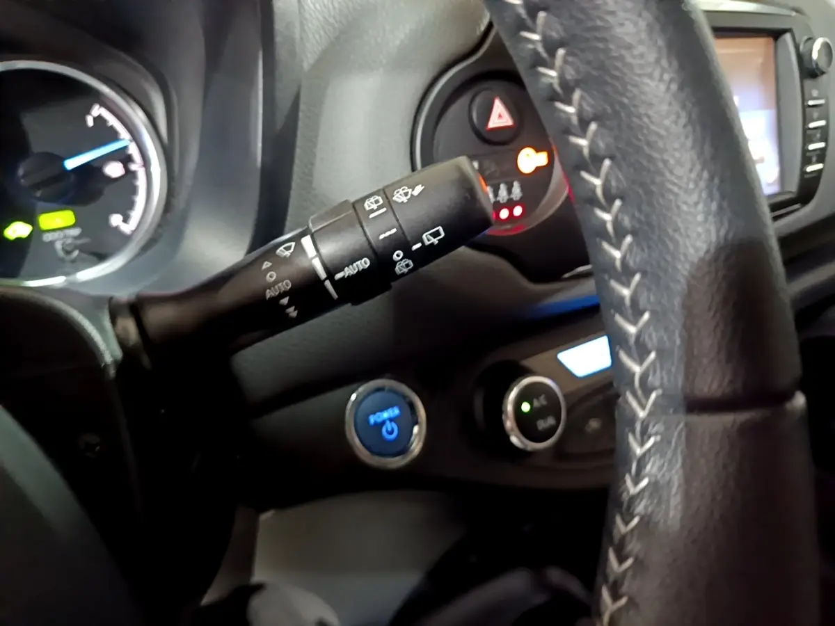 Détail intérieur côté conducteur de la Toyota Yaris blanche 2019, volant cuir et bouton démarrage bleu visible.