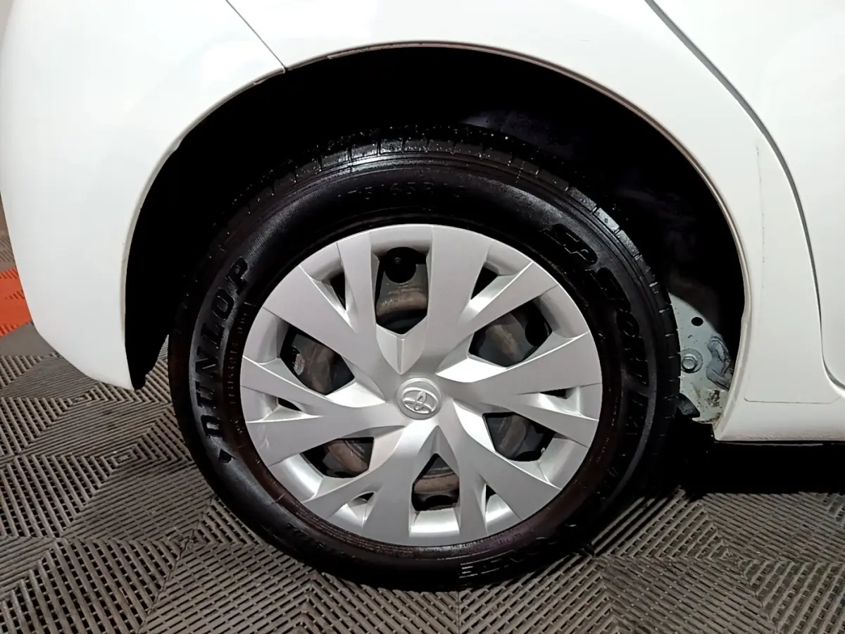 Gros plan sur la roue avant droite blanche d'une Toyota Yaris 1.5 VVT-I Hybrid avec enjoliveur argenté et pneu Dunlop.