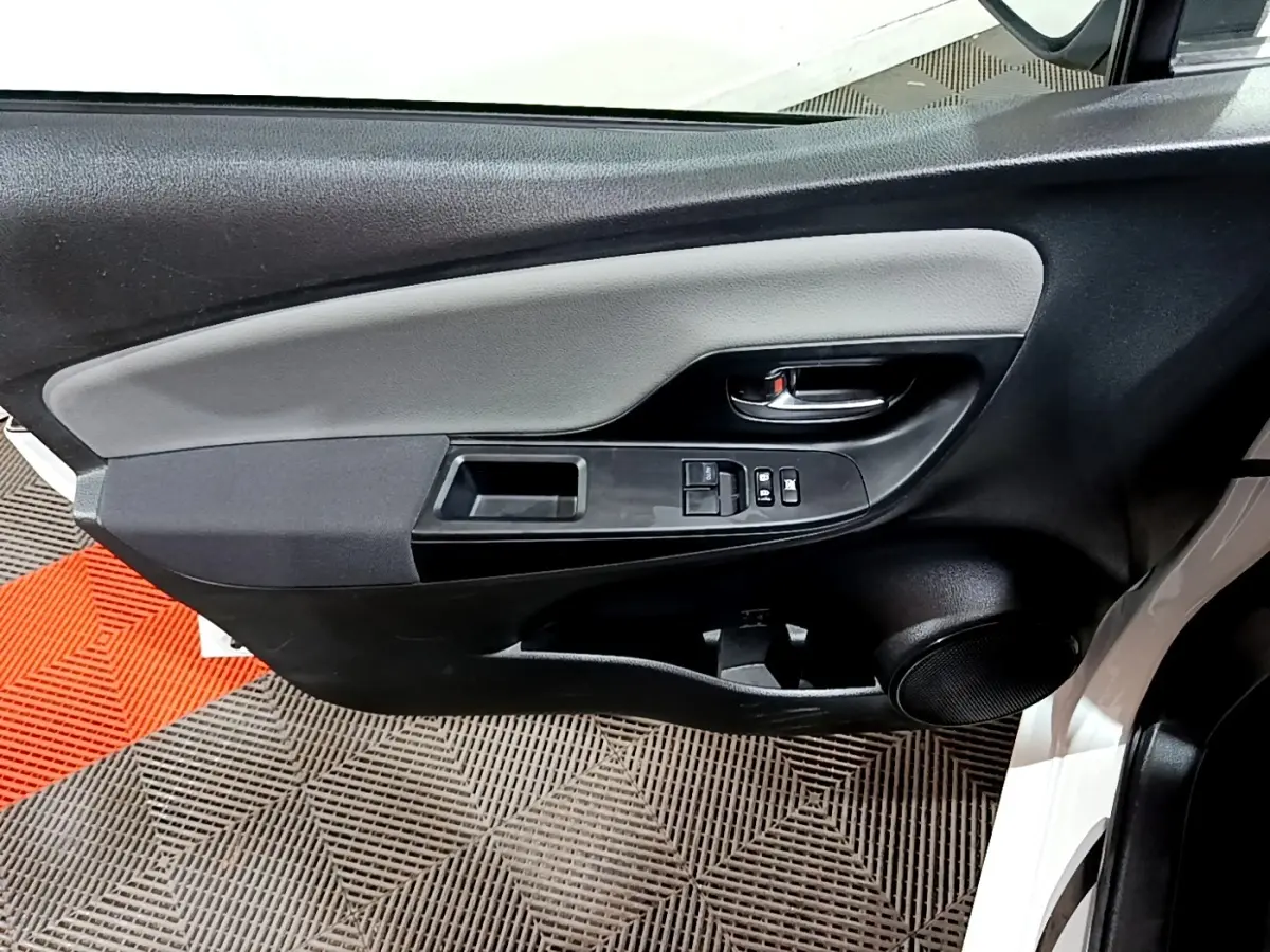 Gros plan sur la porte avant gauche blanche d'une Toyota Yaris 2019, avec commandes électriques et haut-parleur intégré.