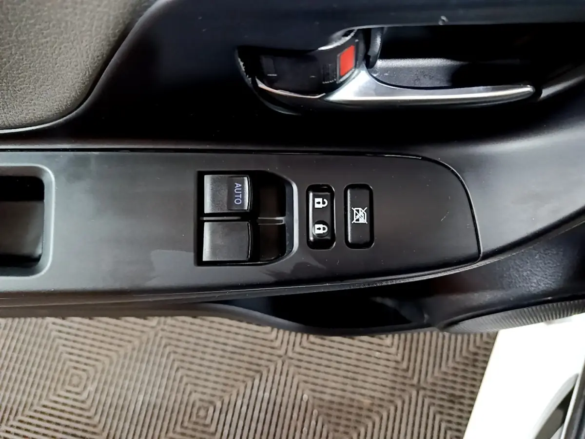 Gros plan sur la commande des vitres et verrouillage côté conducteur de la Toyota Yaris blanche 2019 hybride.