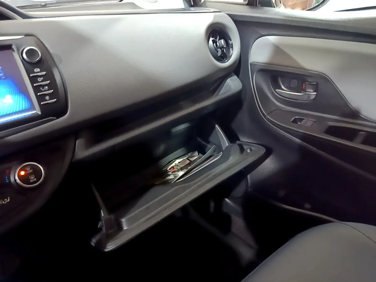 Intérieur de la Toyota Yaris 1.5 Hybrid 2019, vue côté passager avec boîte à gants ouverte et tableau de bord noir.