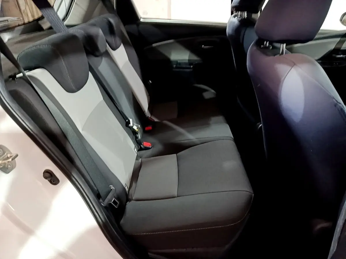 Vue intérieure côté gauche montrant la banquette arrière bi-ton gris foncé et clair de la Toyota Yaris blanche 2019.