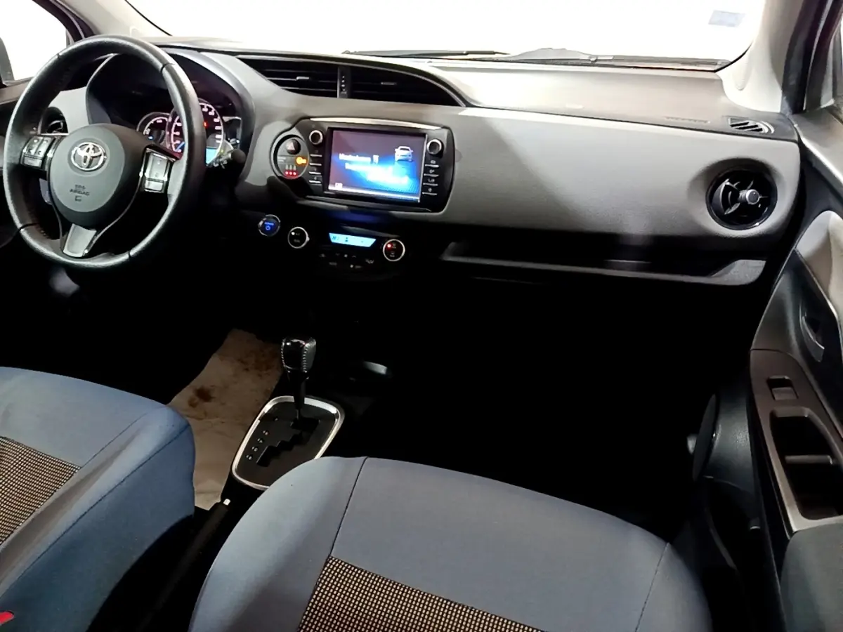 Vue intérieure avant droite de la Toyota Yaris hybride 2019 avec tableau de bord noir et écran tactile central.