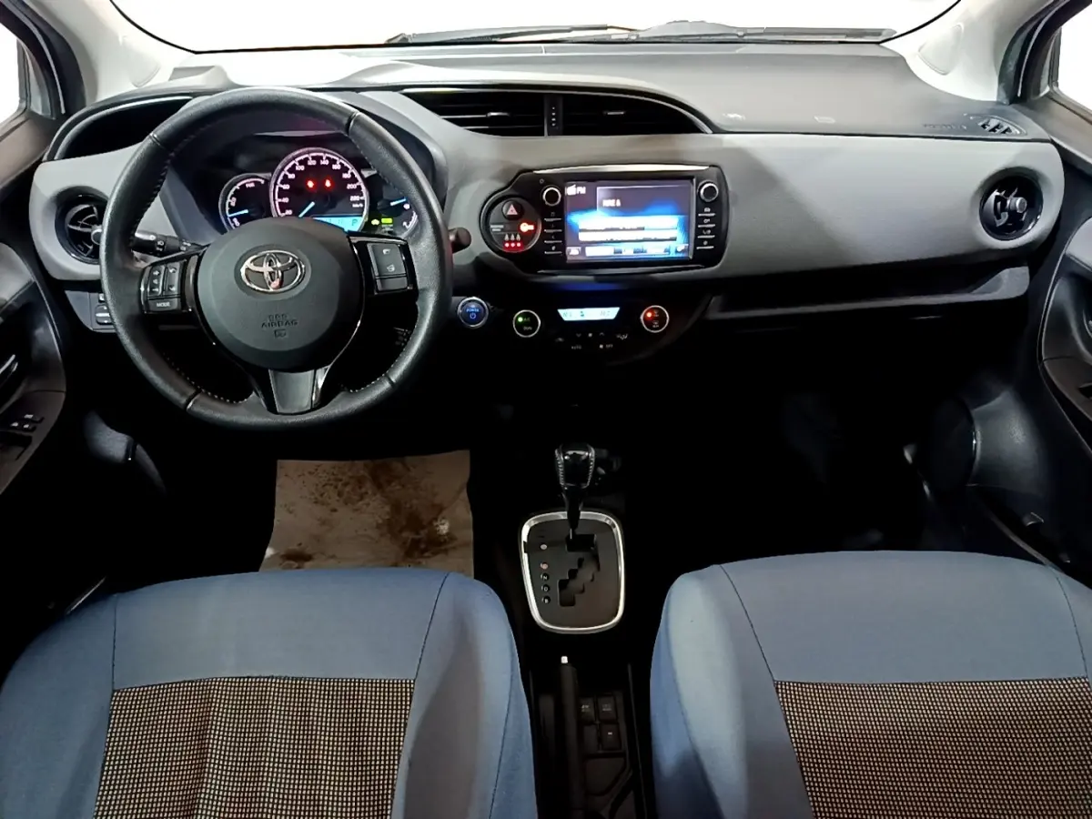 Intérieur de la Toyota Yaris hybride 2019, vue frontale du tableau de bord avec volant cuir et écran tactile central.