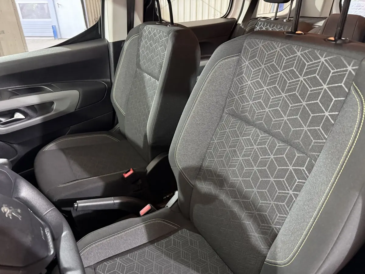 Vue intérieure rapprochée des sièges avant gris à motifs géométriques du Peugeot Rifter blanc, version PureTech 110 S&S Active.