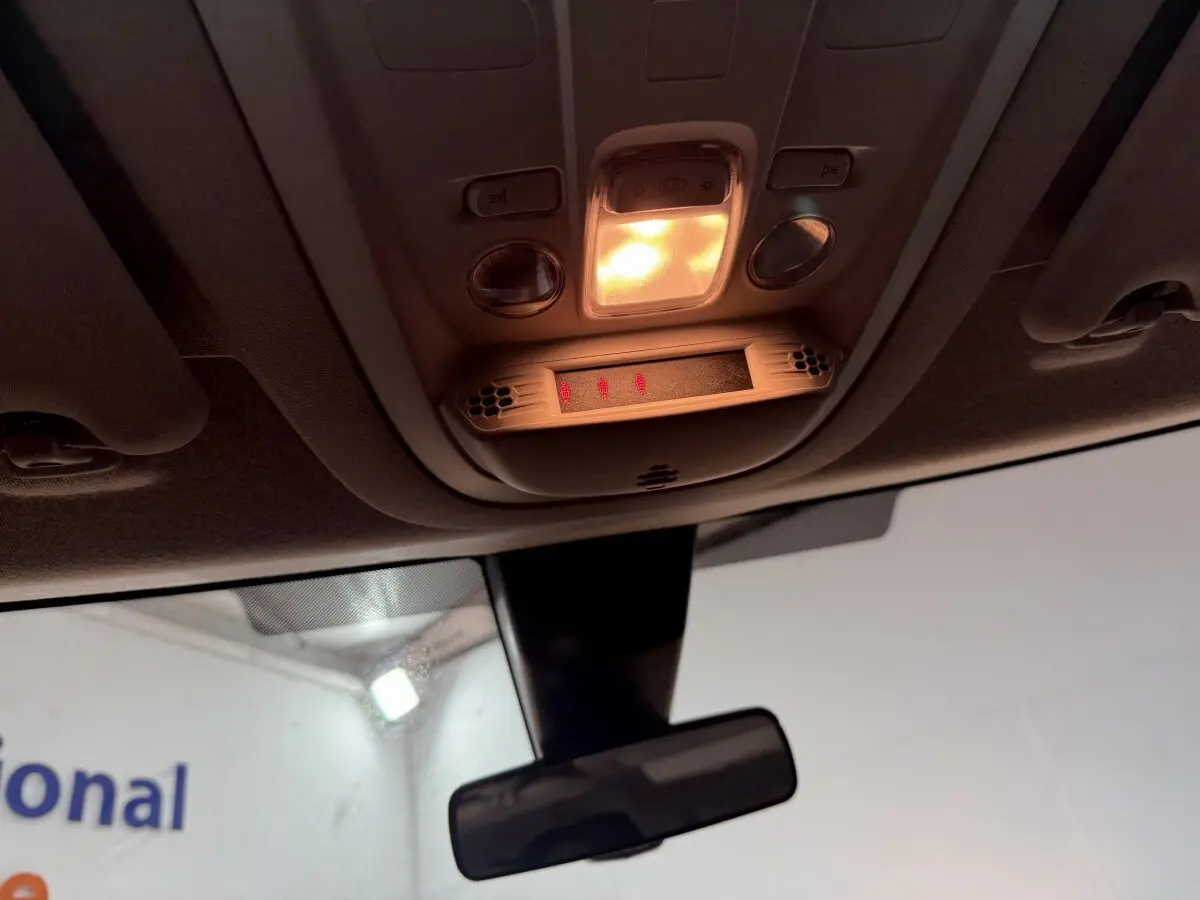 Vue intérieure du plafonnier allumé avec commandes et rétroviseur central d’un Peugeot Rifter blanc 2019.