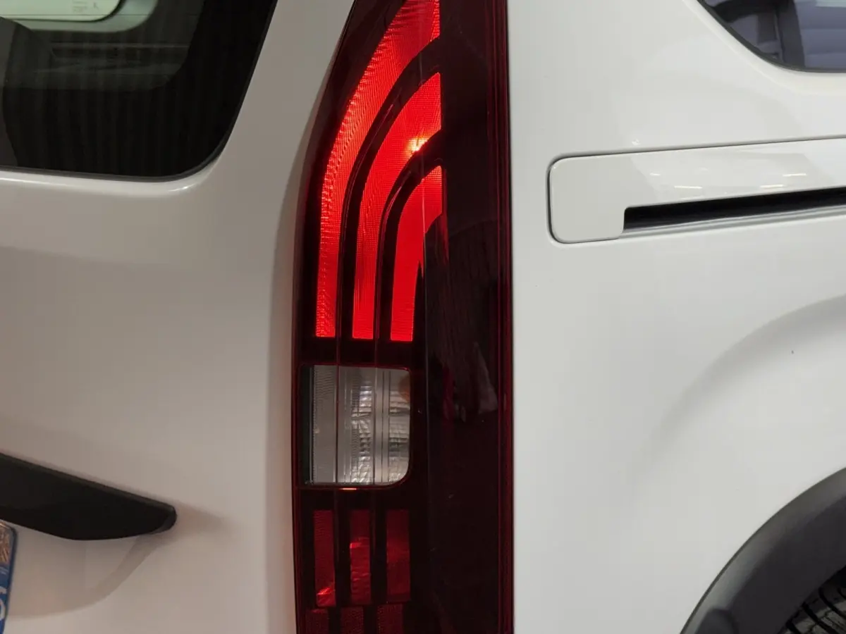 Gros plan sur le feu arrière droit rouge du Peugeot Rifter blanc, avec la portière et la poignée visibles.