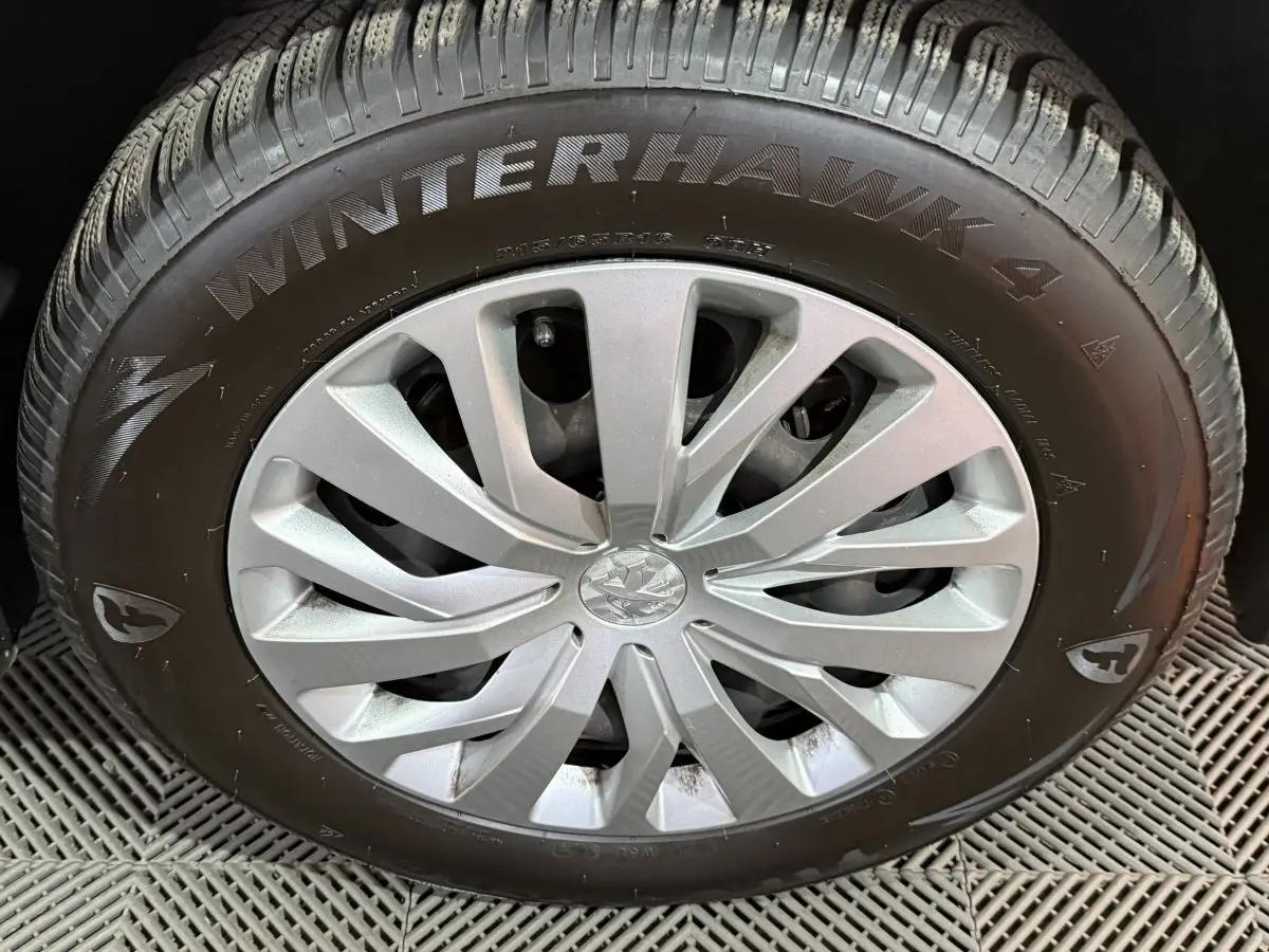 Gros plan sur la roue avant droite du Peugeot Rifter blanc, mettant en valeur la jante argentée et le pneu hiver Winterhawk 4.