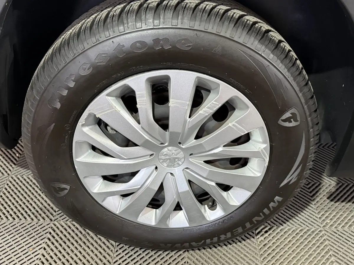 Gros plan sur la roue avant droite du Peugeot Rifter blanc avec jante en alliage et pneu Firestone Winterhawk.