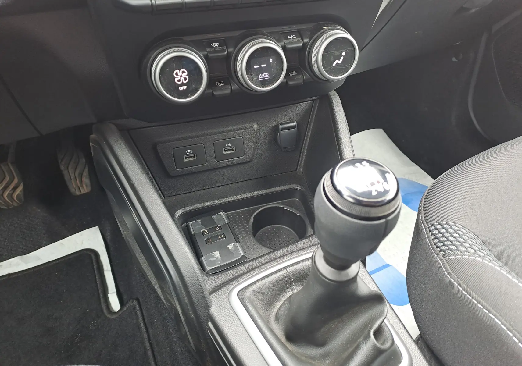 Vue rapprochée de la console centrale du Dacia Duster gris urbain 2024, avec levier de vitesse manuel et commandes de climatisation.