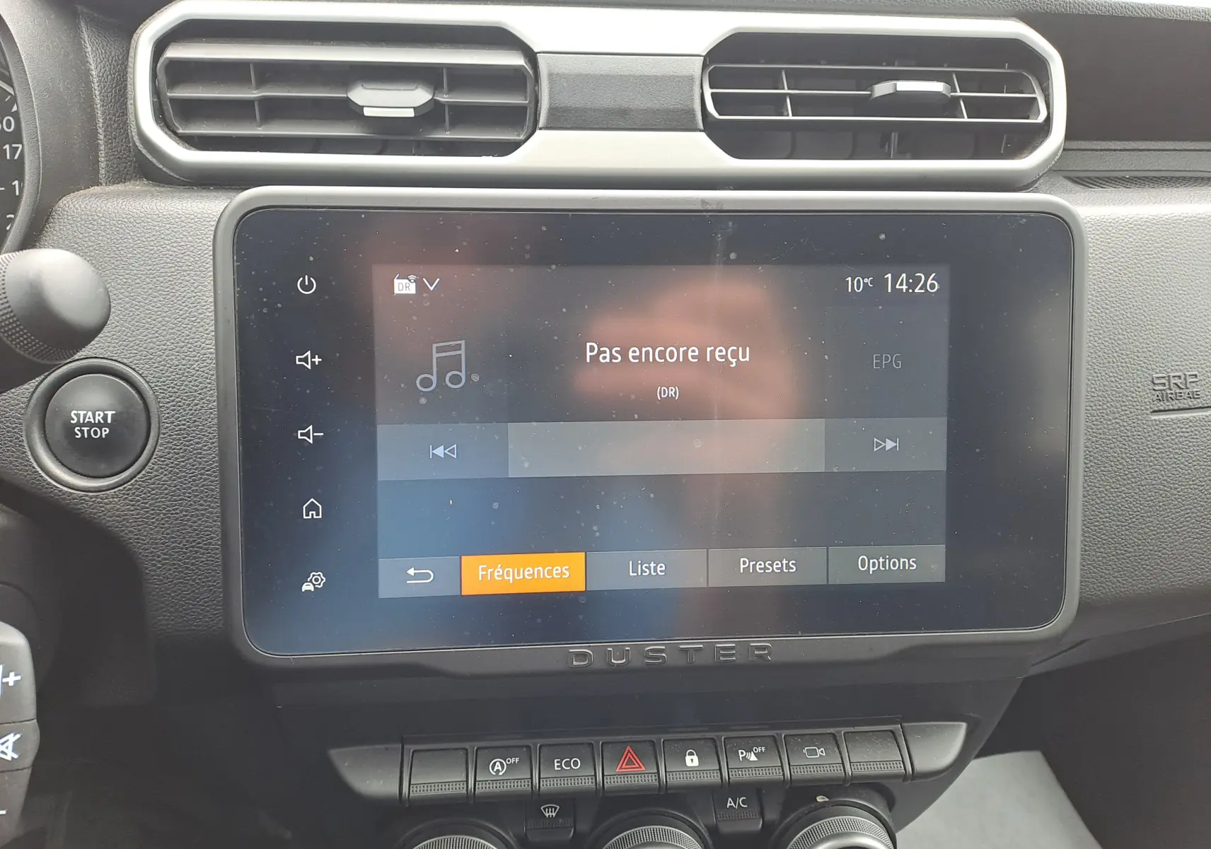 Vue rapprochée de l'écran tactile central et des commandes du tableau de bord du Dacia Duster gris urbain 2024.
