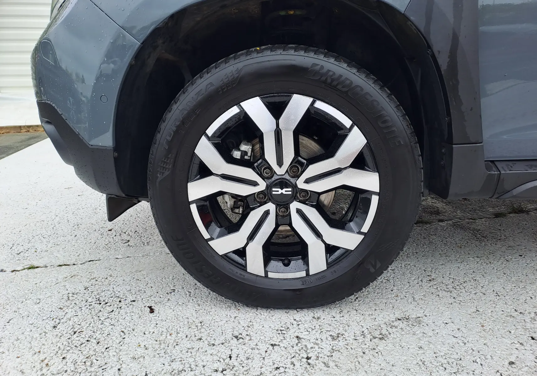 Gros plan sur la roue avant gauche du Dacia Duster gris urbain 2024 avec jante alliage bicolore et pneu Bridgestone.