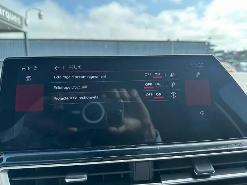 Écran tactile du tableau de bord du Citroën C5 Aircross 2025 affichant les réglages des feux, avec reflet extérieur.