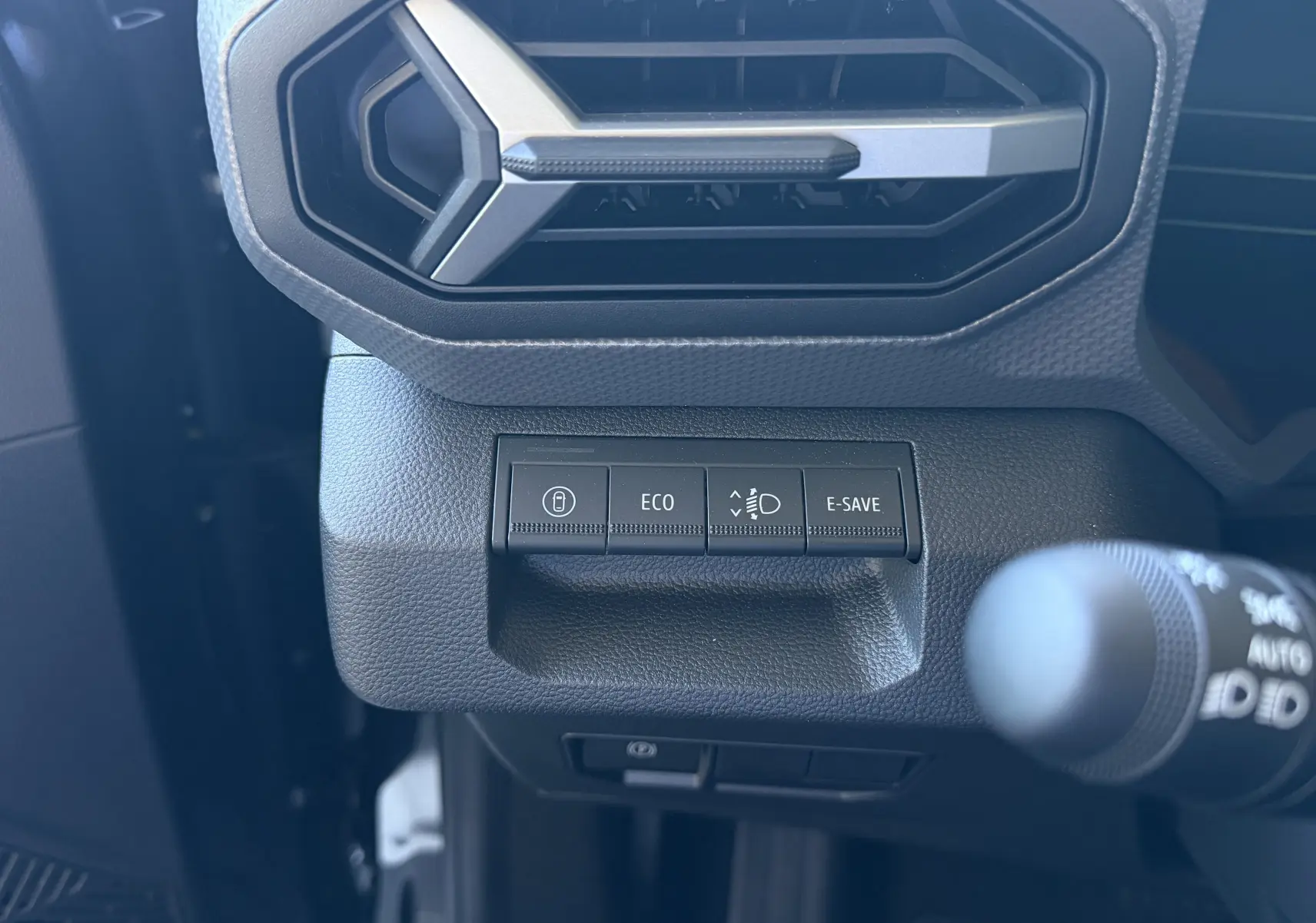 Gros plan sur les boutons de commande noirs sous la sortie d'air hexagonale du tableau de bord du Dacia Duster Hybrid 155 Journey.