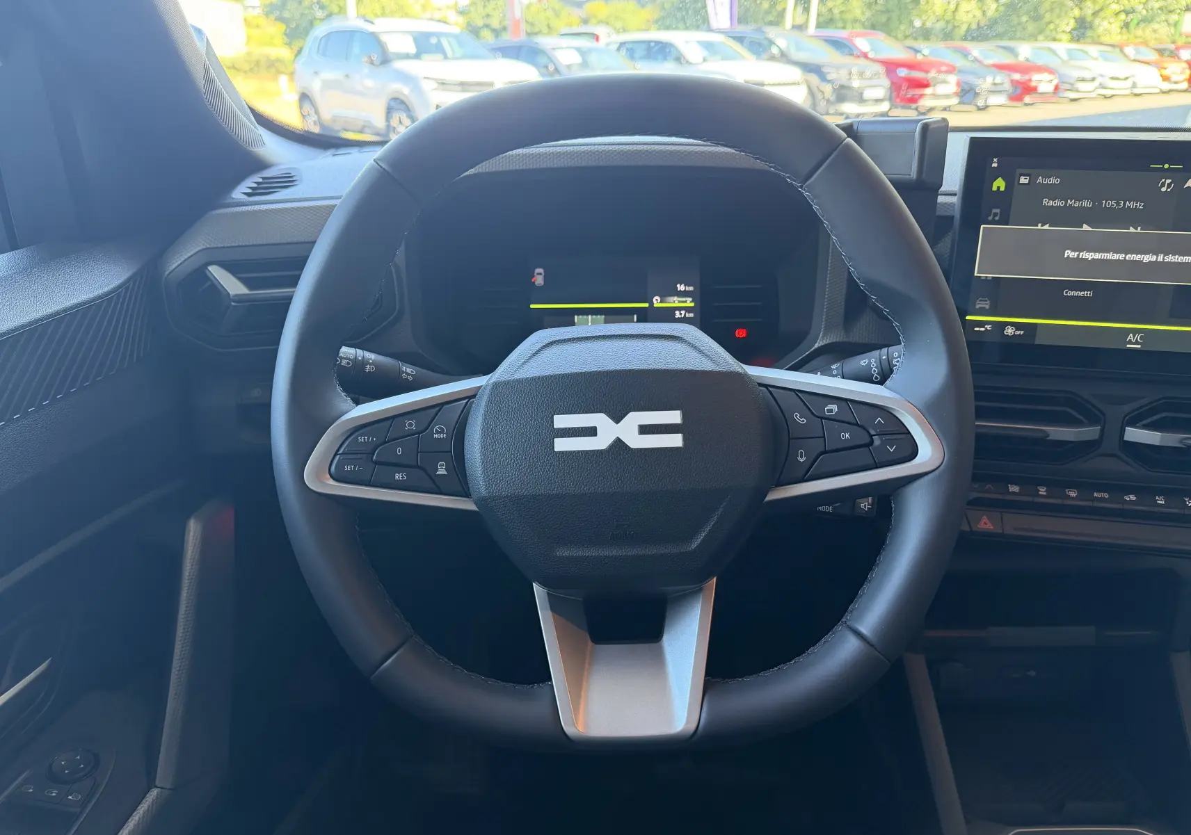 Vue intérieure centrée sur le volant noir du Dacia Duster Hybrid 155 Journey avec tableau de bord et écran tactile.