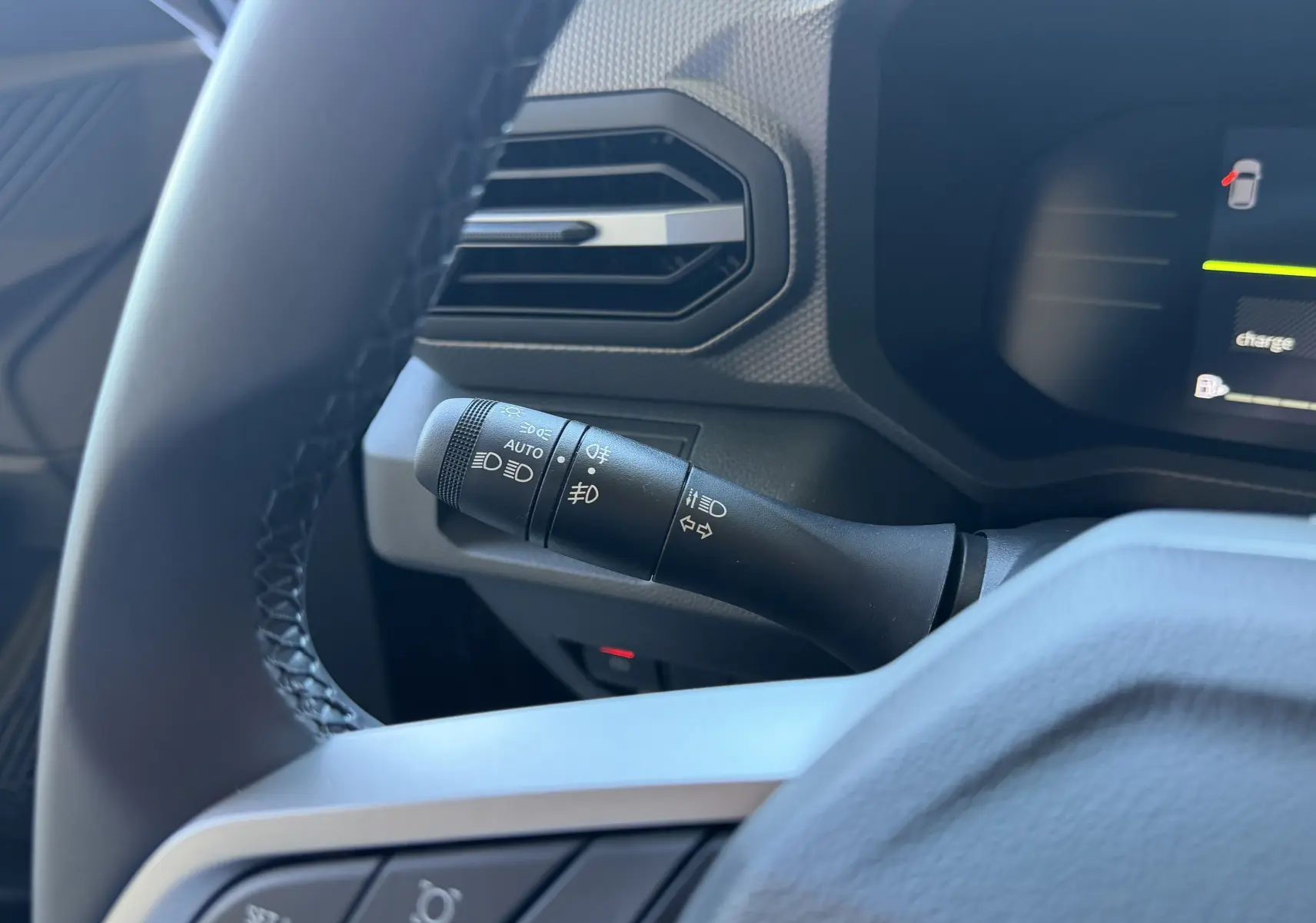 Vue rapprochée du commodo d’éclairage à gauche du volant dans l’habitacle noir du Dacia Duster Hybrid 155 Journey 2026.
