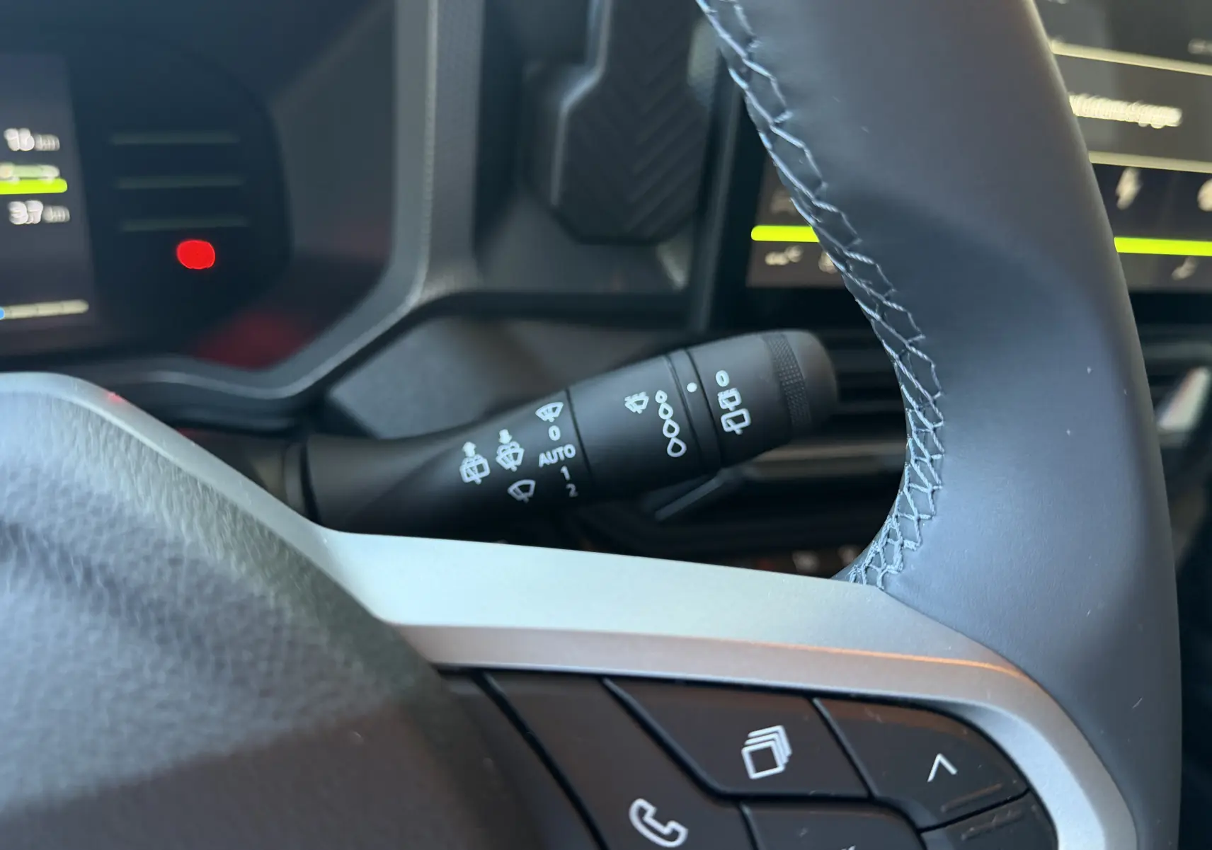 Gros plan sur la commande d’essuie-glace et partie du volant du Dacia Duster Hybrid 155 noir, intérieur côté conducteur.