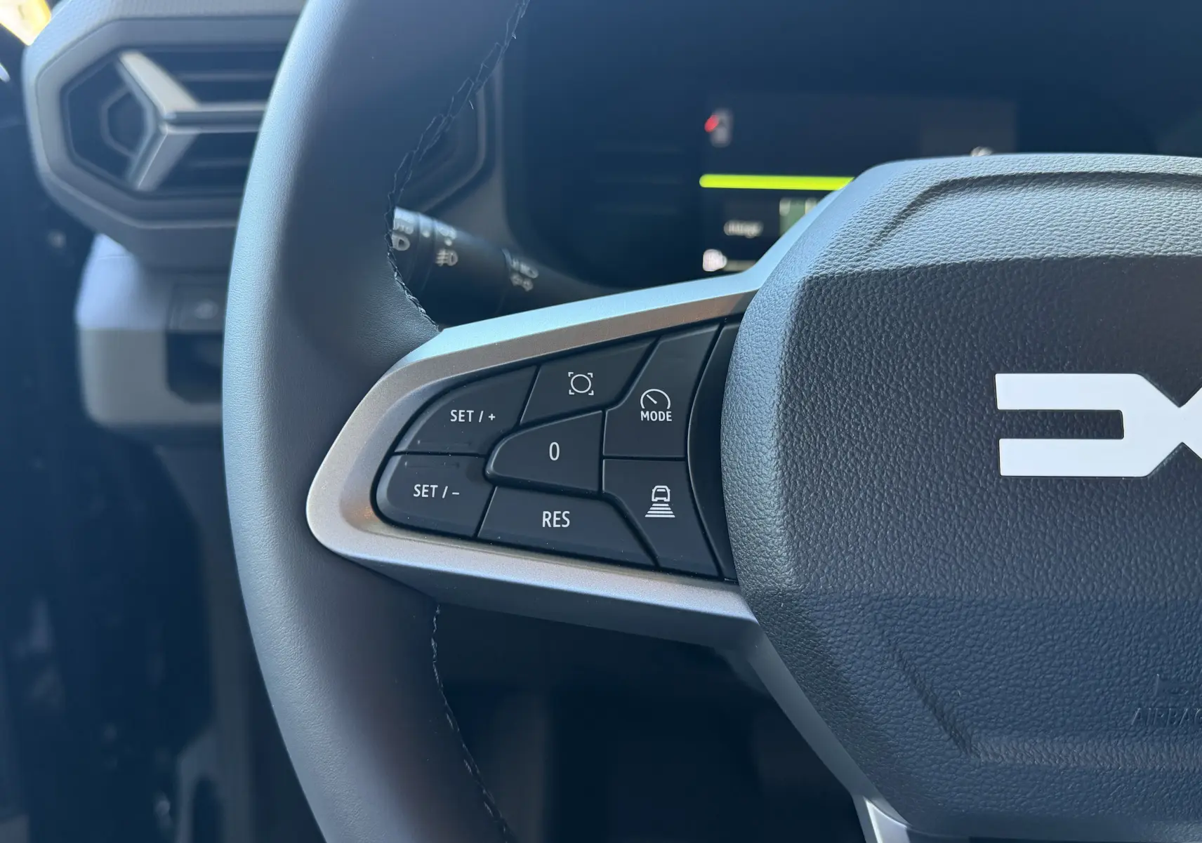 Gros plan sur la partie gauche du volant noir du Dacia Duster Hybrid 155 Journey 2026 avec commandes de régulateur de vitesse.