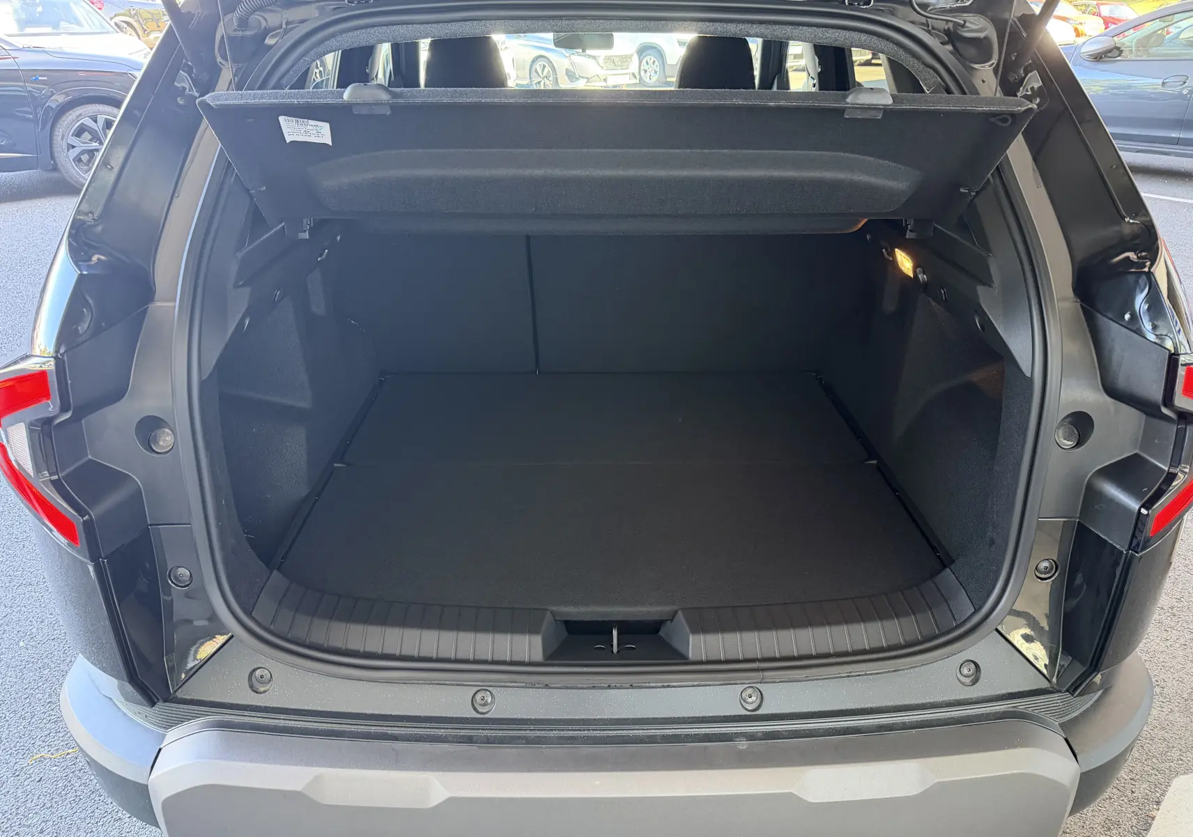 Coffre ouvert vu de l'arrière d'un Dacia Duster Hybrid 155 Journey noir avec hayon levé et intérieur spacieux.