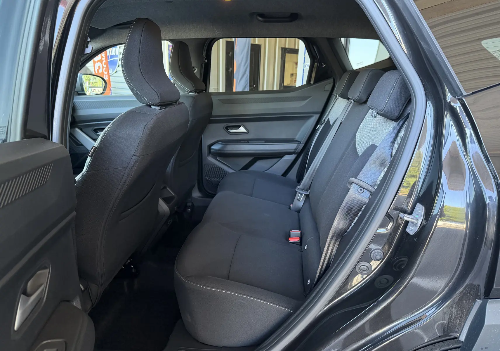 Vue intérieure côté droit des sièges arrière noirs du Dacia Duster Hybrid 155 Journey 2026 avec ceinture de sécurité visible.