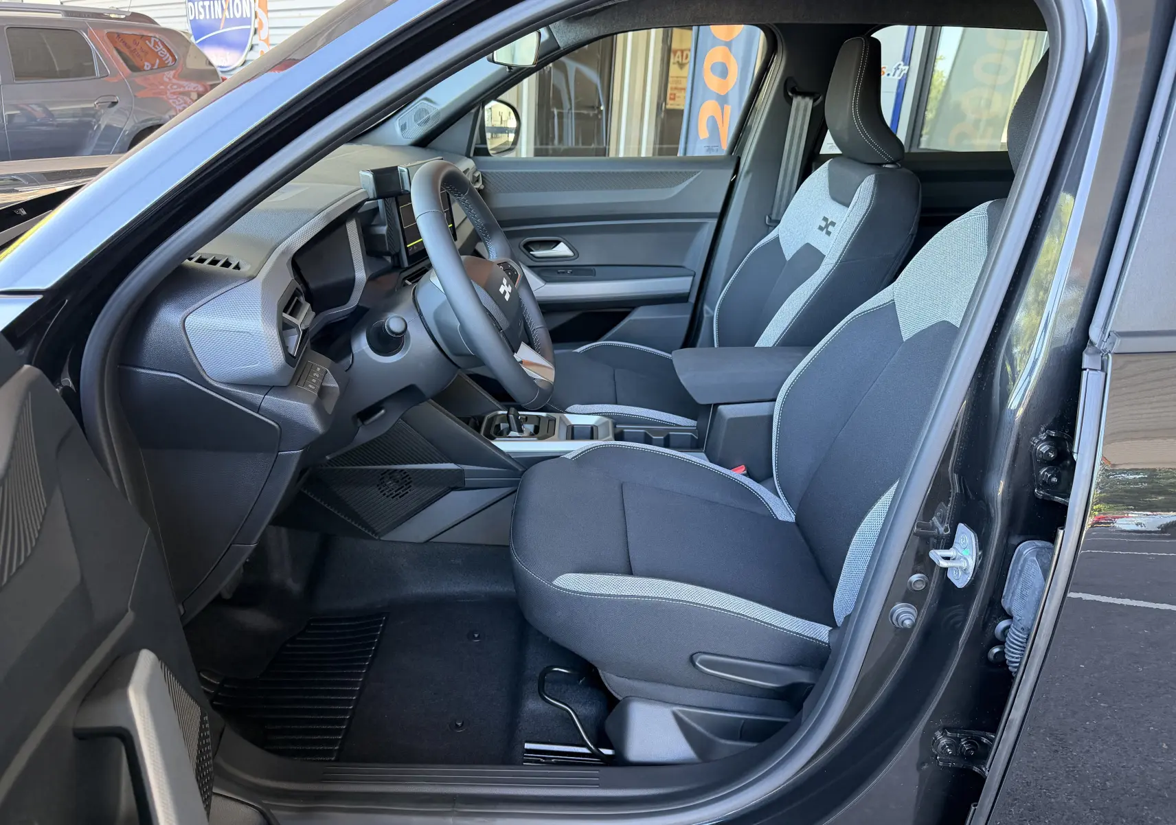 Intérieur du Dacia Duster Hybrid 155 Journey 2026 noir, vue côté gauche montrant les sièges bicolores et le tableau de bord moderne.