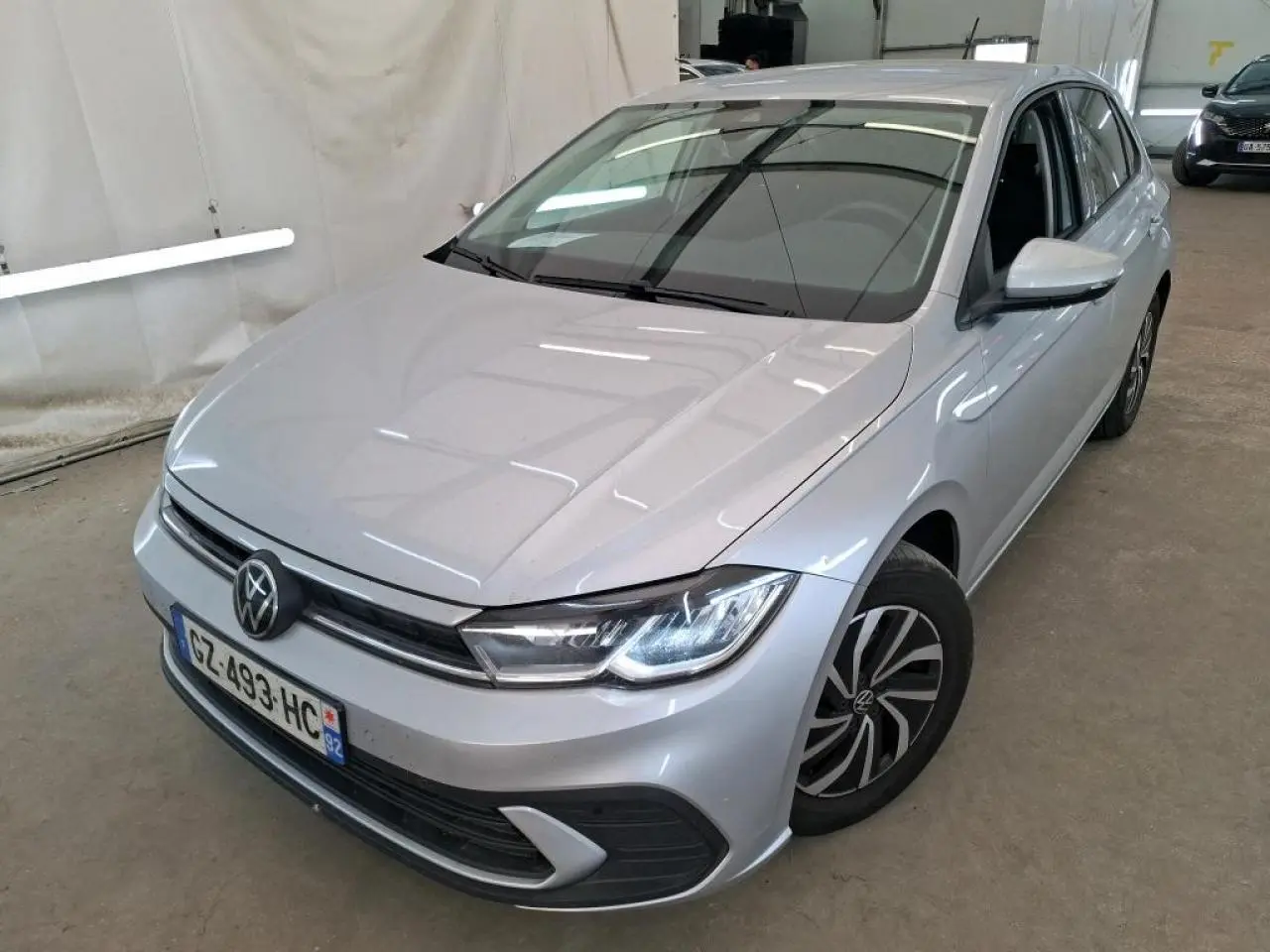 Volkswagen Polo gris clair vue 3/4 avant droit, avec phares LED et jantes alliage distinctives.