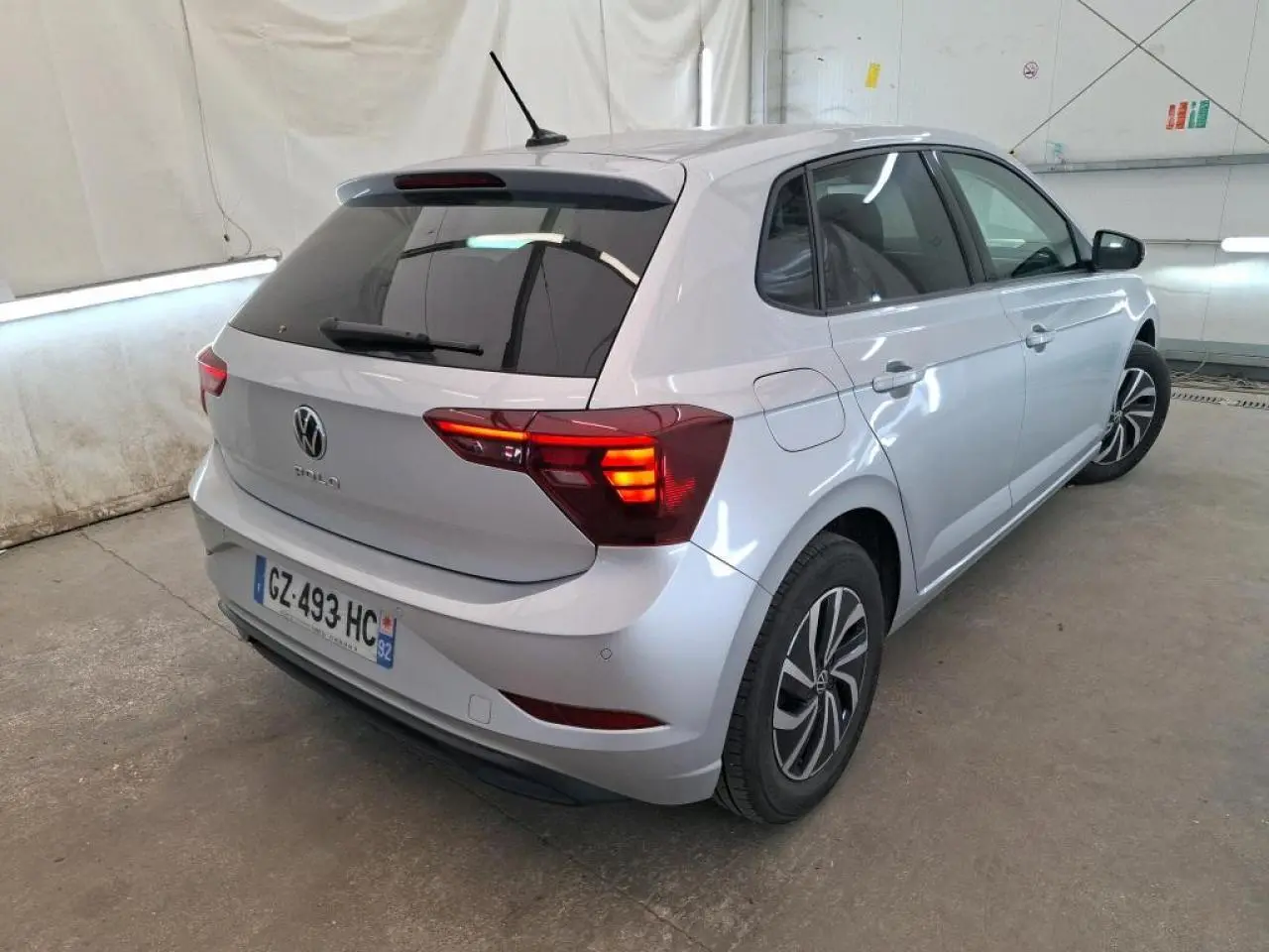 Vue 3/4 arrière droite d'une Volkswagen Polo gris clair avec vitres arrière surteintées et jantes alliage.