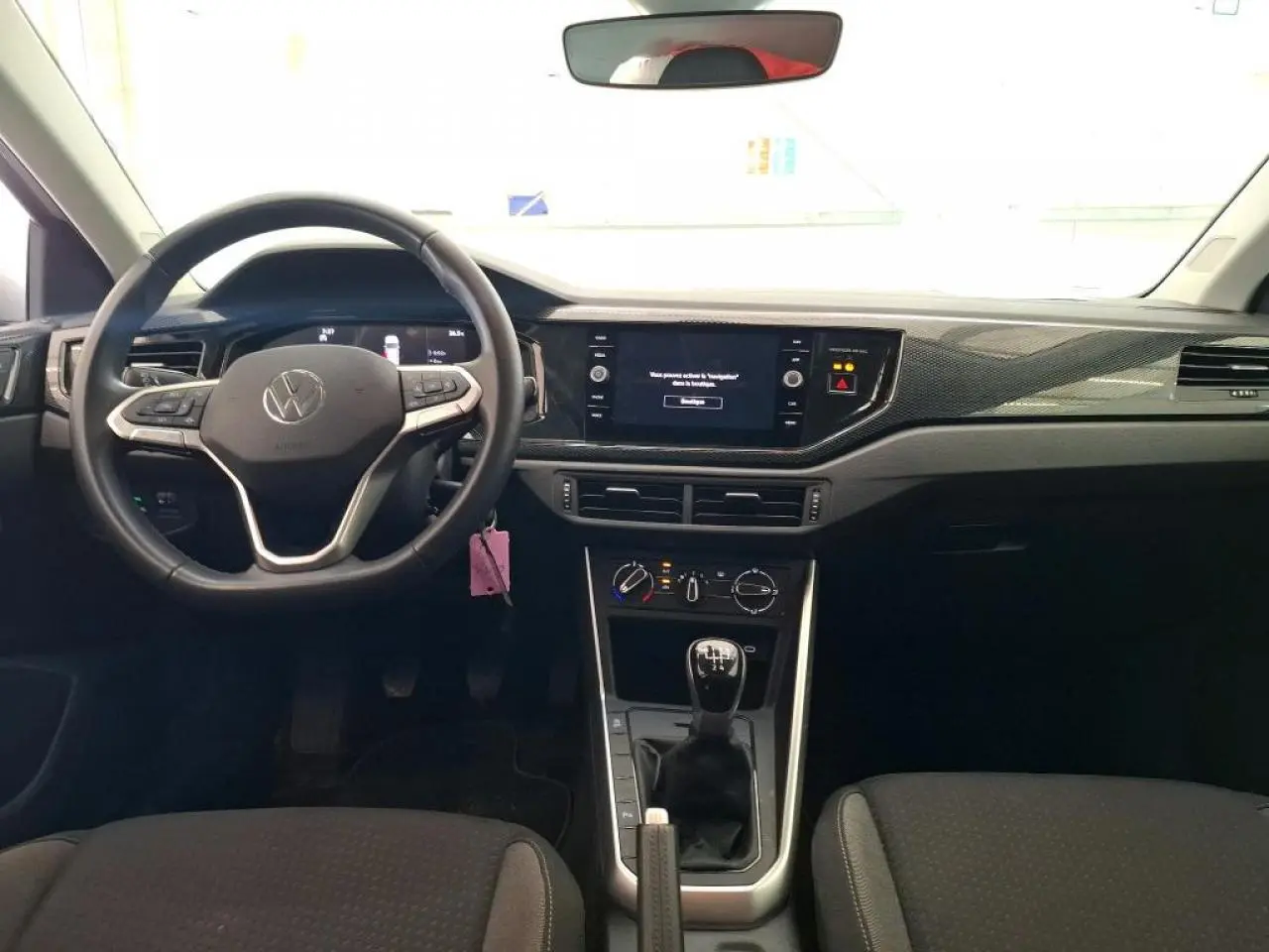 Vue intérieure avant de la Volkswagen Polo gris clair 2024, volant cuir multifonction et levier de vitesses manuel.